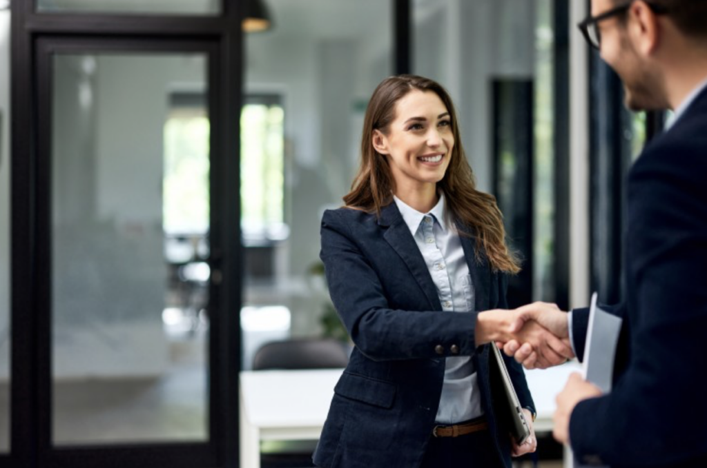 An MBA graduate shakes hands with a potential employer at a job interview